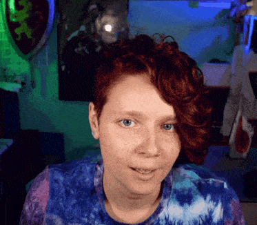 a woman with red hair is wearing a blue and purple shirt