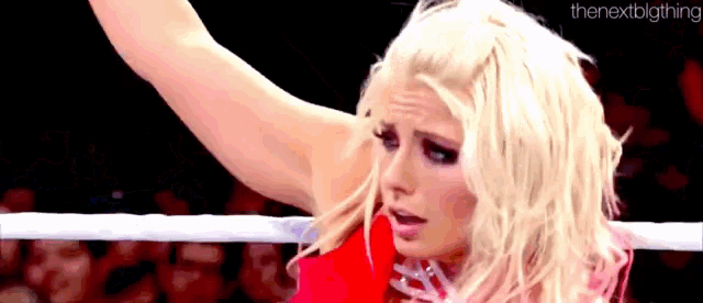 a woman in a red dress is standing in a wrestling ring .