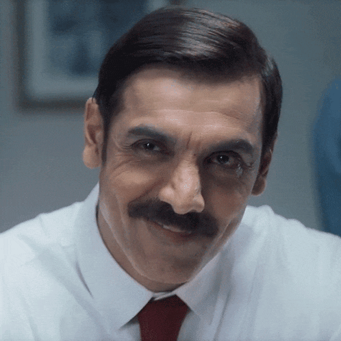 a man with a mustache wearing a white shirt and a red tie