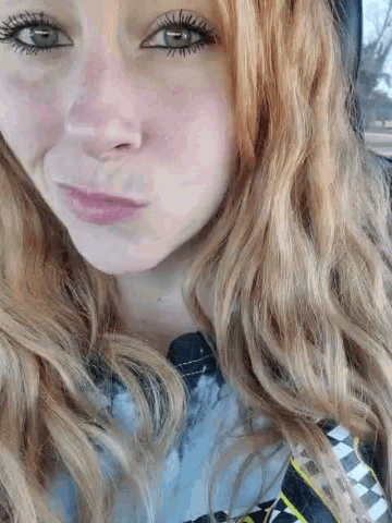 a close up of a woman 's face with long blonde hair and green eyes