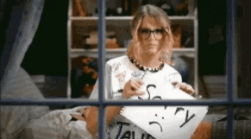 a woman is holding a piece of paper that says sorry