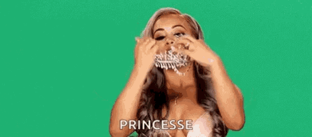 a woman is wearing a tiara on her head and smiling on a green background .
