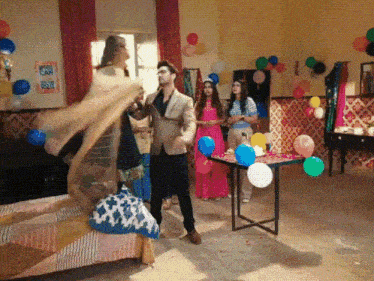 a group of people are dancing in a room decorated with balloons and a sign that says " you can do it "