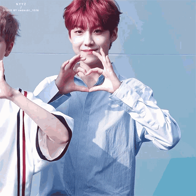 a boy with red hair making a heart with his hands