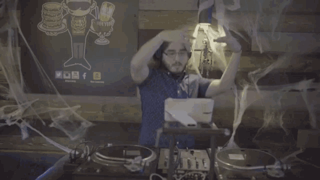 a man wearing headphones is playing a record on a turntable in front of a wall with a sign that says beer
