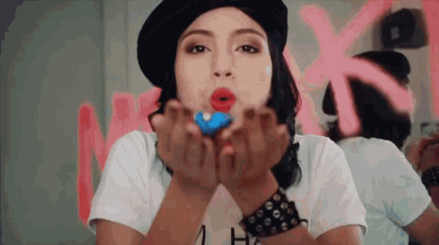 a woman blowing a kiss while holding a donut in her hand