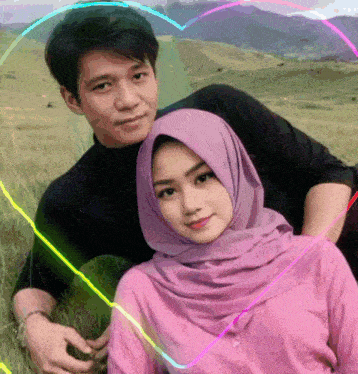 a man and a woman are posing for a picture in a field with a heart in the background