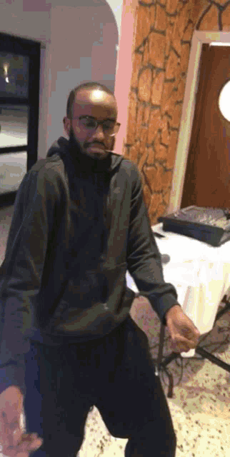 a man in a black hoodie and glasses is dancing