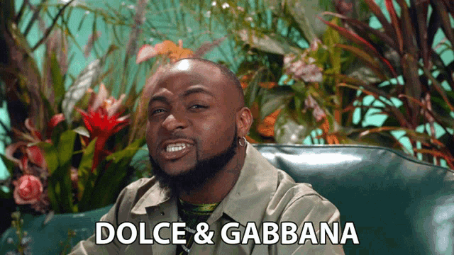 a man sitting on a couch with dolce & gabbana written on the bottom