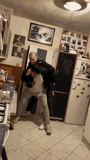 a man is carrying another man on his back in front of a refrigerator