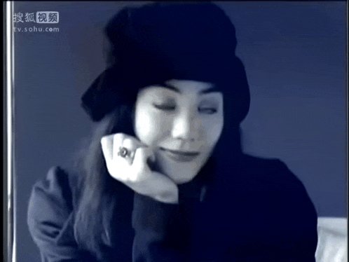 a woman wearing a black hat and a ring is on a tv screen