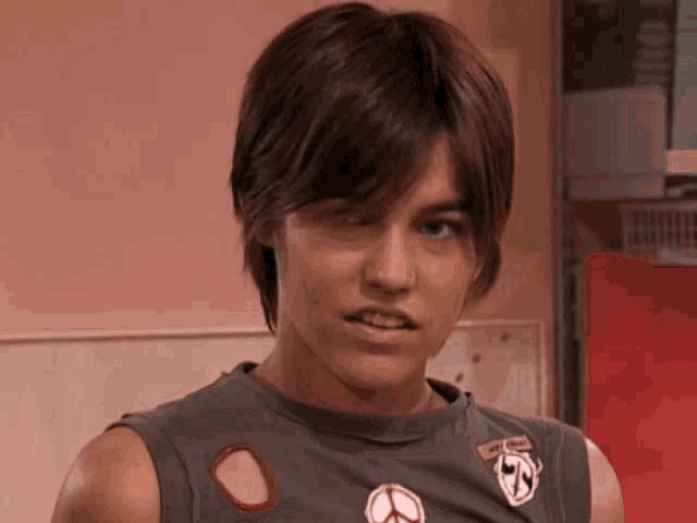 a young man wearing a sleeveless t-shirt with a peace sign on it
