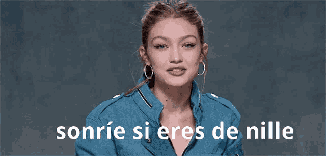 a woman in a blue jacket is smiling with the words sonrie si eres de nille behind her