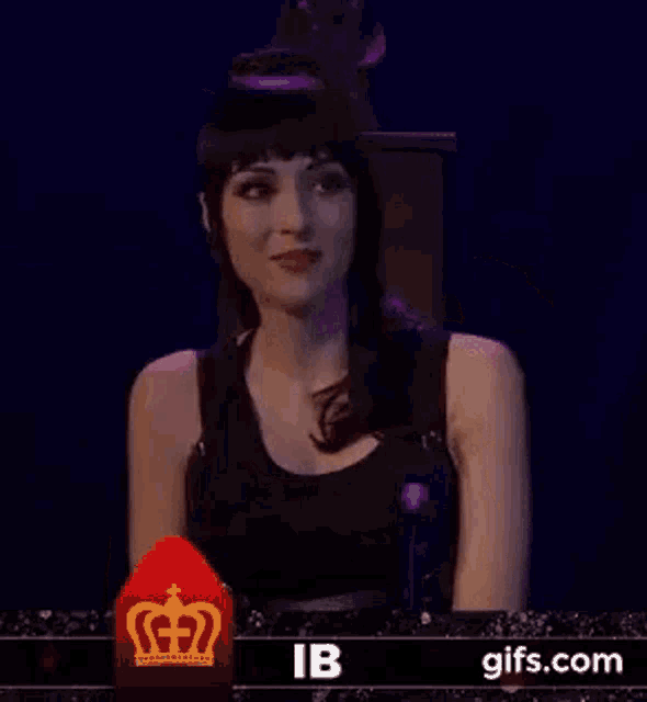 a woman in a black tank top is waving her hand in front of a red crown .