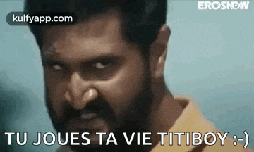 a man with a beard is making a funny face with the words `` tu joues ta vie titiboy '' written on it .