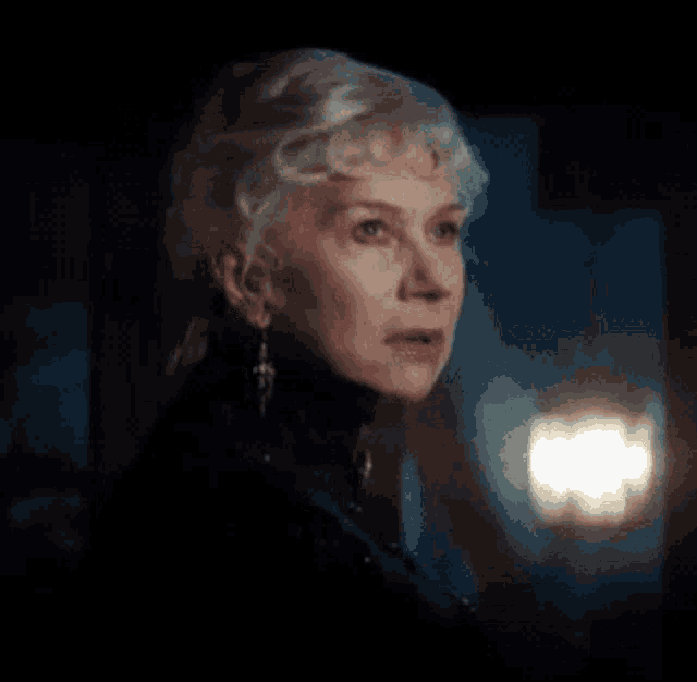 a close up of a woman 's face in a dark room with a light behind her