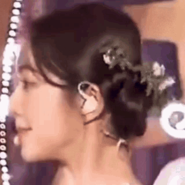 a close up of a woman 's face with a bun in her hair and earrings .