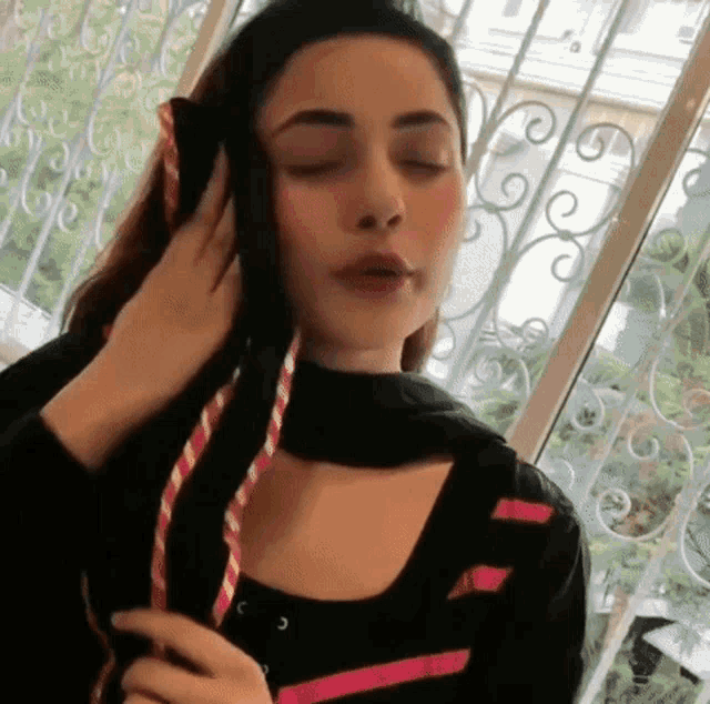 a woman with her eyes closed is wearing headphones .