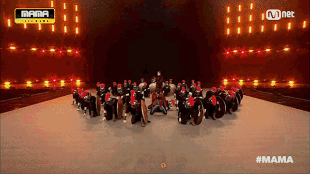 a group of people are dancing on a stage with a yellow sign that says mama on it