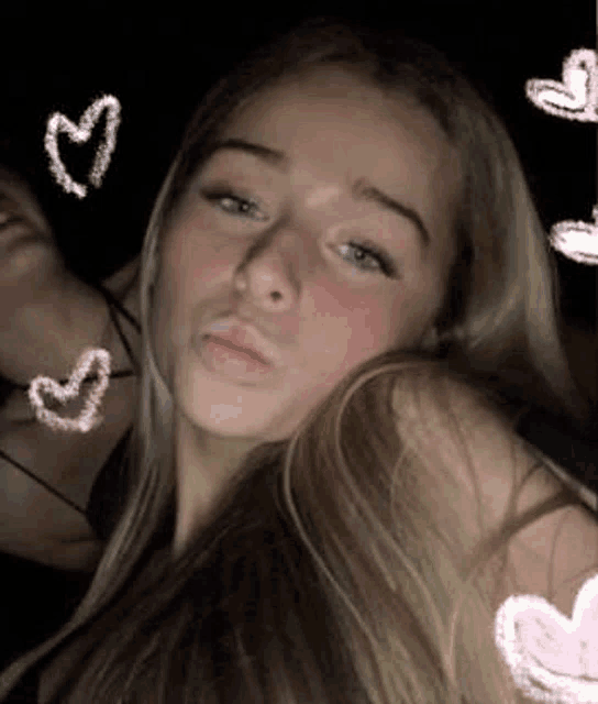 a girl is taking a picture of herself with hearts around her .
