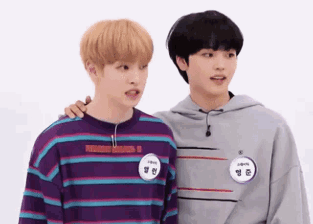 a couple of young men are standing next to each other .