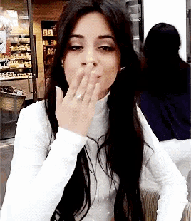 a woman with long hair is blowing a kiss with her hand