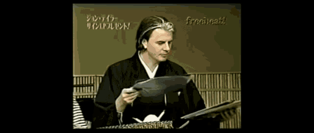 a man is holding a record in front of a sign that says ' freecat '