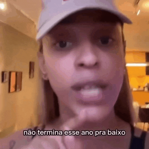 a close up of a woman wearing a hat and saying `` não termina esse ano pra baixo ''
