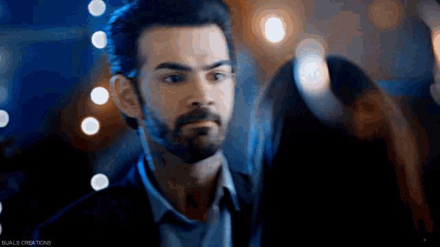 a man with a beard is looking at a woman in a dark room