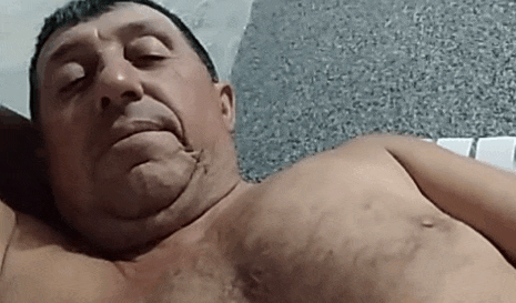 a shirtless man is laying on a bed with his eyes closed and his mouth open .