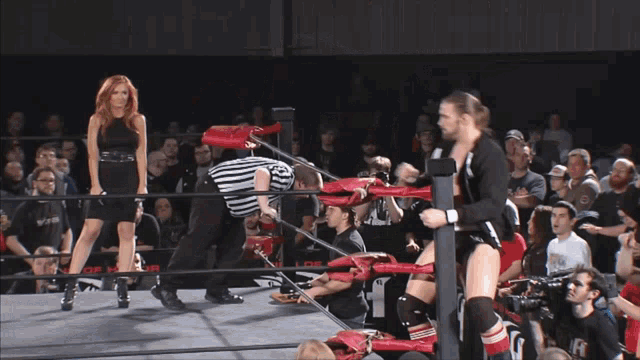 a wrestler is doing a handstand in a wrestling ring while a referee watches