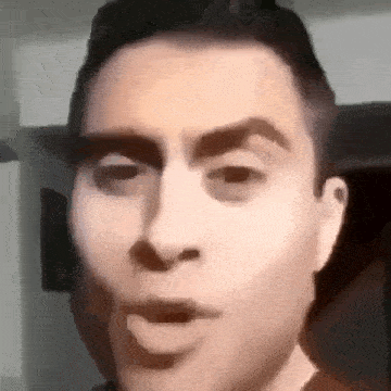 a close up of a man 's face with his mouth open and a blurred background .