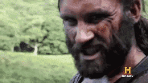 a man with a beard is making a funny face while standing in a field .