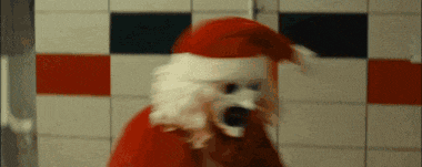 a dog wearing a santa hat and a santa suit is standing in a bathroom .