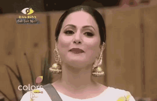 a close up of a woman wearing earrings and a white top