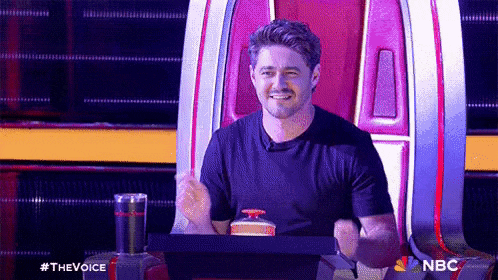 a man in a black shirt is sitting in a chair on a stage .