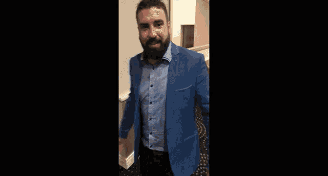 a man with a beard wearing a blue jacket and striped shirt