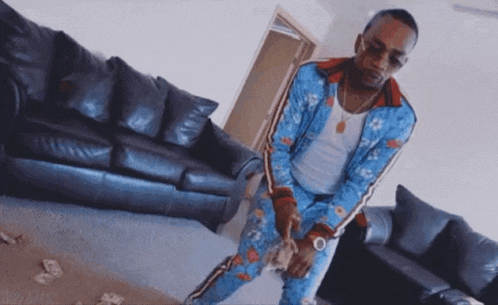 a man in a blue suit is standing in front of a couch holding money