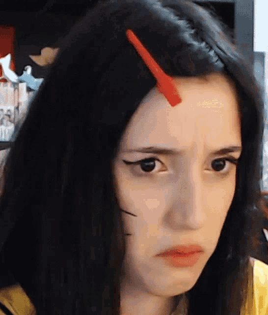 a close up of a woman 's face with a red hair clip on her forehead