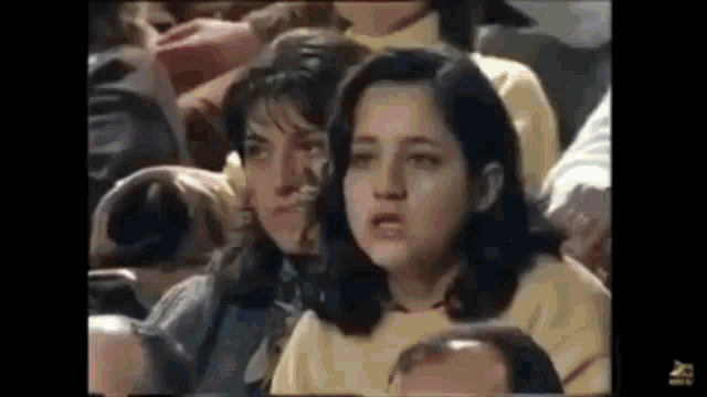a group of people are sitting in a stadium and one of them is making a face .