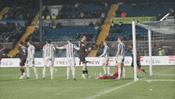 a group of soccer players are on a field with a turnbulls tyres sign in the background