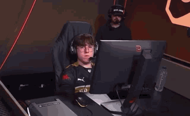 a man wearing headphones is sitting in front of a computer with the letter e on the monitor