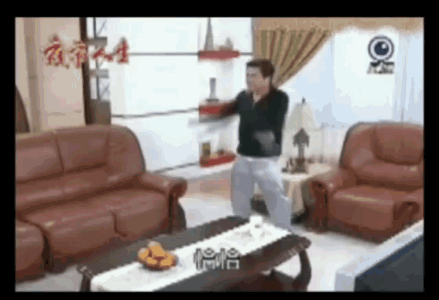 a man is standing in a living room in front of a couch and a coffee table with chinese writing on it