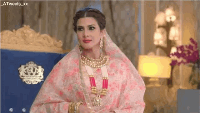 a woman in a wedding dress and jewelry is sitting on a chair .