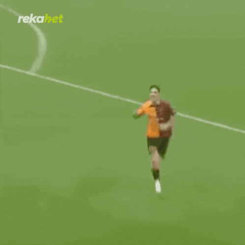 a soccer player wearing a red and orange jersey with the letter s on it is running on the field .