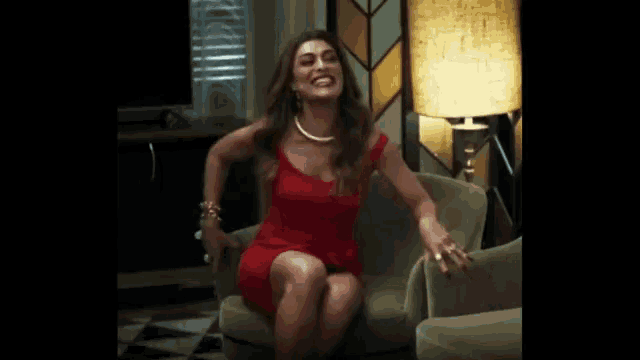a woman in a red dress is sitting on a couch .