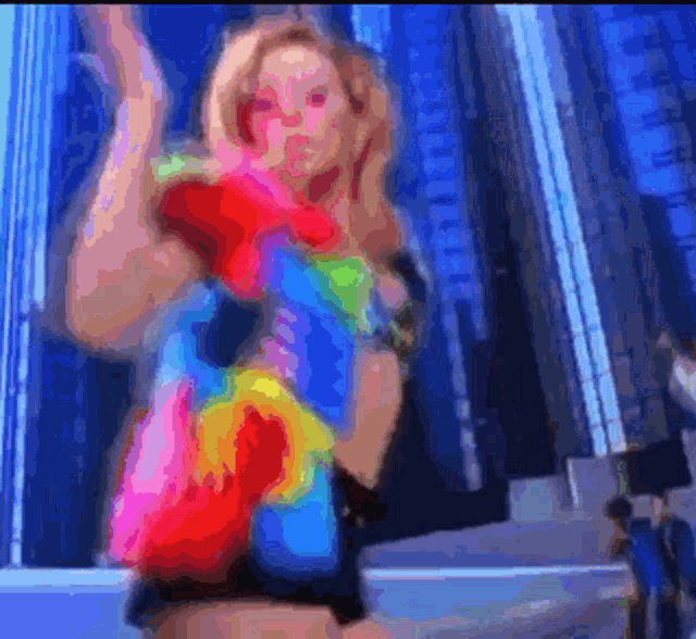 a woman in a colorful dress is dancing in front of a tall building
