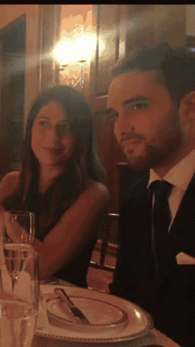 a man in a suit and tie sits next to a woman