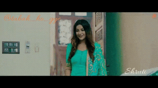 a woman in a green dress is standing in front of a door in a room .