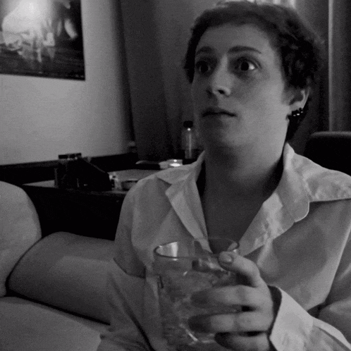 a black and white photo of a woman holding a glass of water